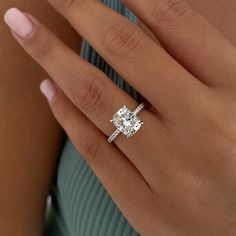 a woman's hand with a diamond ring on her finger and the other hand holding an engagement ring