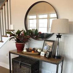 a table with a basket and some plants on it next to a mirror in a room