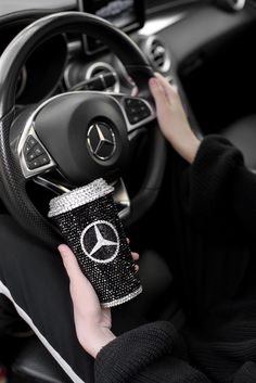 a person holding a cup in their hand while sitting in the driver's seat of a car