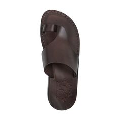 Embrace the sleek contours of the 'Petra' sandal, a silhouette that perfectly balances modern design with classic comfort. Crafted from smooth, full-grain brown leather, this sandal offers a chic and streamlined appearance that complements any outfit. The 'Petra' is a testament to skilled craftsmanship, with a form-fitting design that promotes natural foot movement. Its padded footbed provides a soft, cushioned feel, ideal for day-long wear. A simple, elegant toe loop and a wide upper strap ensu Classic Brown Flip Flops For The Beach, Classic Brown Flip Flops For Beach, Classic Leather Footbed Sandals For Summer, Classic Leather Slides With Single Toe Strap, Classic Brown Slides With Leather Sole, Classic Brown Slides With Leather Lining, Classic Brown T-strap Sandals With Open Toe, Brown Footbed Sandals With Single Toe Strap For Summer, Classic Brown Open Toe T-strap Sandals