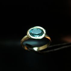 a gold ring with a blue topazte stone in the center on a black background