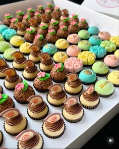 an assortment of decorated cupcakes in a box