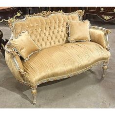 an antique couch with gold velvet upholster and pillows on it's back