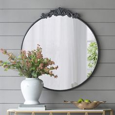 a white vase sitting on top of a wooden table next to a mirror and shelf