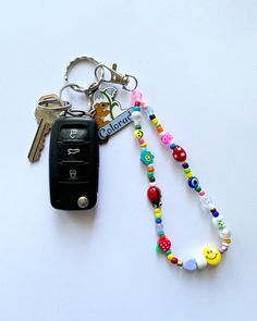 a car key chain with beads on it and a smiley face charm attached to it