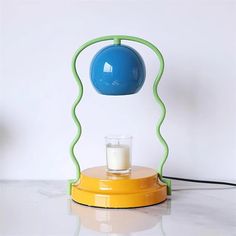 a yellow and green table lamp with a glass of milk on it's base