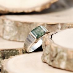 a green ring sitting on top of a piece of wood next to a slice of tree