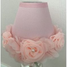 a pink lamp shade with flowers and pearls on the bottom is sitting on a table