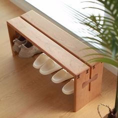 a wooden bench with two pairs of shoes on it next to a potted plant