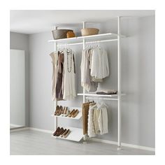 a white closet with clothes and shoes hanging on the wall next to an open door