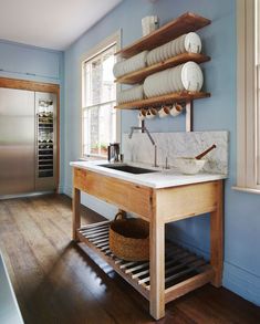 a kitchen with blue walls and wooden shelves filled with dishes on top of the counter