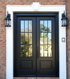 a black double door with two sidelights and brick wall in front of the house