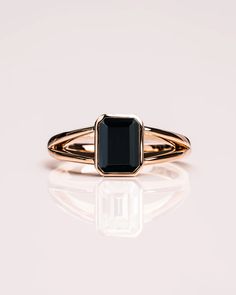 a gold ring with a black stone in the center and a thin band around it