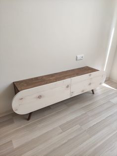 a large white wooden cabinet sitting on top of a hard wood floor next to a window