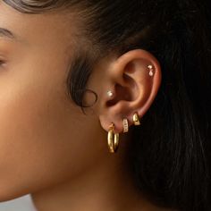 a close up of a person with ear piercings and an earring in gold