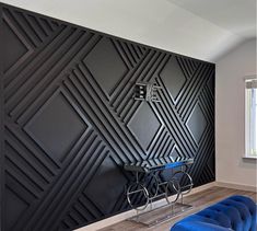 a blue couch sitting in front of a black wall with geometric designs on the walls