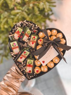 a heart shaped box filled with assorted chocolates on top of a table next to a potted plant