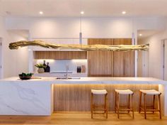 a kitchen with marble counter tops and wooden stools next to an island in the middle