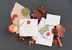 wedding stationery with autumn leaves, apples and envelopes on grey fabric tablecloth