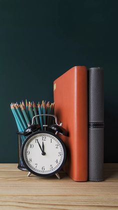 an alarm clock, books and pencils on a table