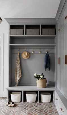 a bench with baskets and coat hooks on it in the entryway to a home