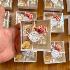 a hand holding a small box filled with tiny candies and other candy items on top of a wooden table