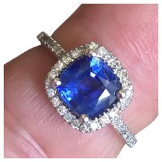 a close up of a person's hand holding a ring with a blue stone