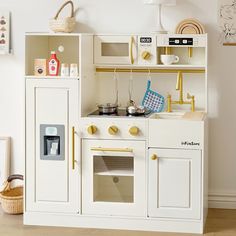 a toy kitchen with white cabinets and gold trim on the doors, drawers and shelves