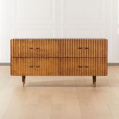 a wooden dresser sitting on top of a hard wood floor next to a white wall