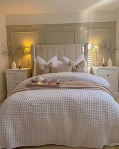 a bed with pillows and blankets in a bedroom next to two lamps on either side of the bed