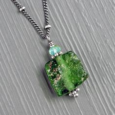 "This one of a kind minimalist pendant necklace features a unique ancient Roman glass square shaped bead in a vibrant deep green with hints of blue. The surface of the bead is wonderfully both smooth and rough, so satisfyingly \"crunchy\" and imperfect. I've paired the ancient glass bead with a tiny faceted Peruvian opal and small granulated sterling silver beads, all carefully wrapped with sterling silver wire. It comes on a chain of your choice in either 16\" or 18\" lengths, make your selection from the drop down menu. Roman glass was the first mass produced glass, circa the first century AD they developed a technique that made production easier and faster than ever known before. This resulted in the massive growth of the Roman influence at the end of this period and Roman glass found i Spiritual Rectangular Jade Jewelry, Minimalist Jade Gemstone Jewelry, Everyday Green Glass Jewelry, Fusion Style Czech Glass Jewelry Gift, Fusion Style Czech Glass Jewelry For Gifts, Minimalist Jade Jewelry As A Gift, Minimalist Jade Jewelry For May Birthstone, Minimalist Adjustable Glass Jewelry, Minimalist Handmade Rectangular Jewelry