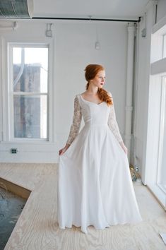 a woman in a white dress standing on a wooden floor with her hands behind her back