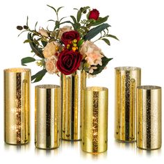 gold vases with flowers in them on a white surface and one has red roses