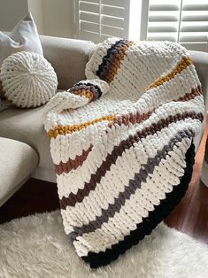 a white couch with a multicolored blanket on top of it next to pillows