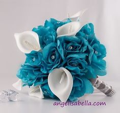 a bridal bouquet with blue flowers and diamond brooches on the bottom, in front of a white background