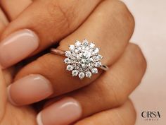 a woman's hand holding an engagement ring with diamonds on the top and bottom