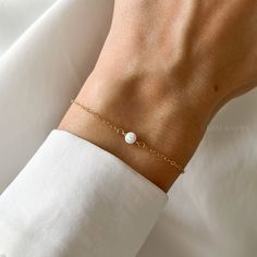 Discover our Opal Bracelet, perfect for giving a touch of sparkle to any outfit. Made to fit your style in sterling silver, 14k gold filled, or 14k solid gold, it's adjustable to get just the right fit. Details: ✦ Features a shiny 4mm Fire & Snow Opal. ✦ Choose your chain type: 14k Solid Gold, 14K Gold-Filled, or 925 Sterling Silver. ✦ Comes in a pretty gift box, ready to give. ✦ Sizes available: 6+1" or 7+1" with an extra 1-inch extension for easy adjusting. Need it bigger or smaller? Let us kn Elegant White Birthstone Jewelry, Minimalist Formal Bracelet With Simple Design, White 14k Gold Pearl Bracelet, Minimalist 14k White Gold Bracelets, Dainty Jewelry With Simple Design For Formal Occasions, Minimalist White Gold Pearl Bracelet Gift, White 14k Gold Bracelet, Adjustable White 14k Gold Jewelry, Minimalist 14k Gold Filled Bracelets For Anniversary