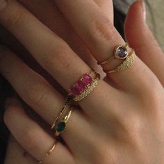 a woman's hand with two rings on it and one ring has three different colored stones