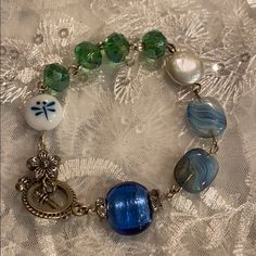 a bracelet with glass beads and charms on a lace tablecloth covered surface in closeup