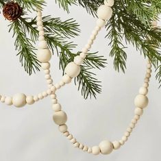 a wooden beaded ornament hanging from a christmas tree with pine cones on it