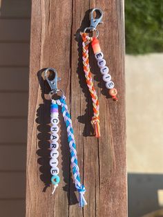 two colorful key chains hanging from a wooden post