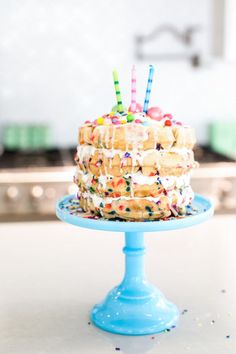 a cake on a blue plate with sprinkles and candles sticking out of it