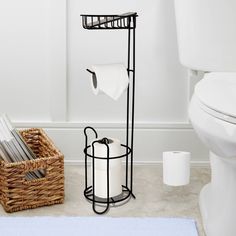 a white toilet sitting next to a basket on top of a bathroom floor near a toilet paper dispenser