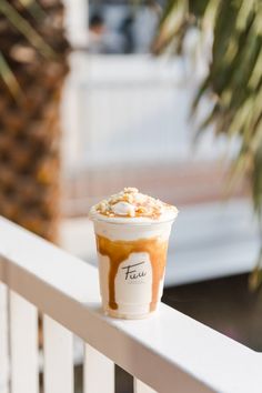 an iced coffee with caramel drizzled on top sitting on a white railing