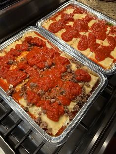 two pans of lasagna sitting on top of an oven