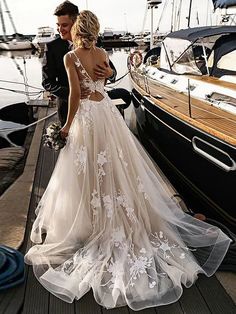 a man and woman standing on a dock next to boats