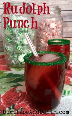 two glasses filled with red liquid sitting on top of a table next to candy canes