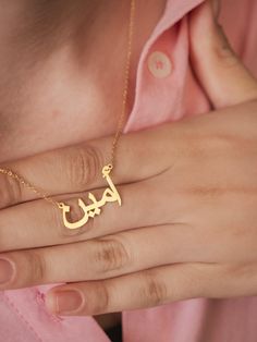 This personalized 14K gold Arabic name necklace promises to become a cherished symbol of your heritage and elegance. Imagine the grace and sophistication it will add to your look as you adorn your neck with this exquisite piece. Crafted with meticulous attention to detail, this necklace will become a timeless treasure, reflecting the beauty of the Arabic language and culture. The intricate calligraphy of your name will create a truly personalized and meaningful piece that will be admired for gen Name Necklace Arabic, Arabic Name Necklace, Arabic Jewelry, Islamic Jewelry, Arabic Calligraphy Design, Arabic Names, Arabic Language, Calligraphy Design, Special Jewelry