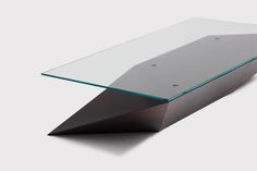 a modern glass and wood coffee table with an angled design on the top, in front of a white background