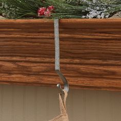 a close up of a metal hook on a wooden shelf with christmas decorations in the background